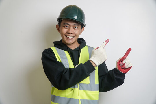 Smiling Asian Man in Safety Vest and Hard Hat Pointing with Both Index Fingers