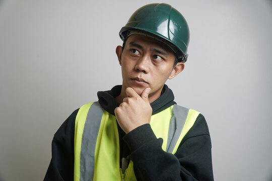 Asian Male Construction Professional in Hard Hat and Reflective Vest Looking Pensive