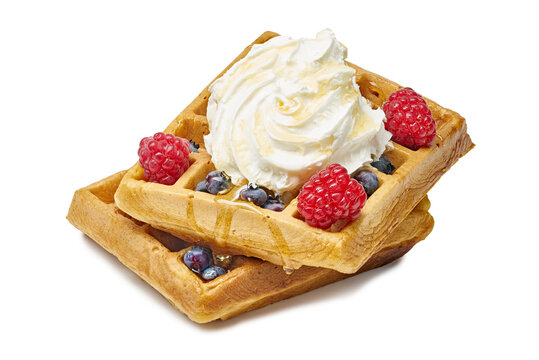 waffles decorated with raspberries and blueberries and whipped cream on a white background viewed from above, delicious and appetizing breakfast food dessert snack.