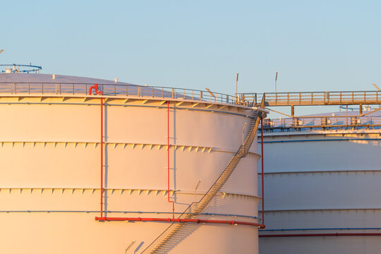 Large oil storage tanks at an industrial refinery facility. Petroleum and fuel storage reservoir tanks in a chemical production plant.