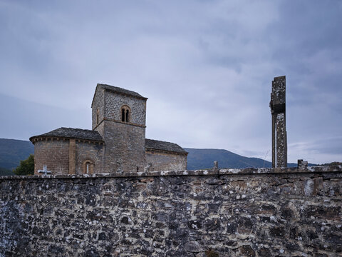 Historic romanesque church and ancient stone cross standing in the cemetery