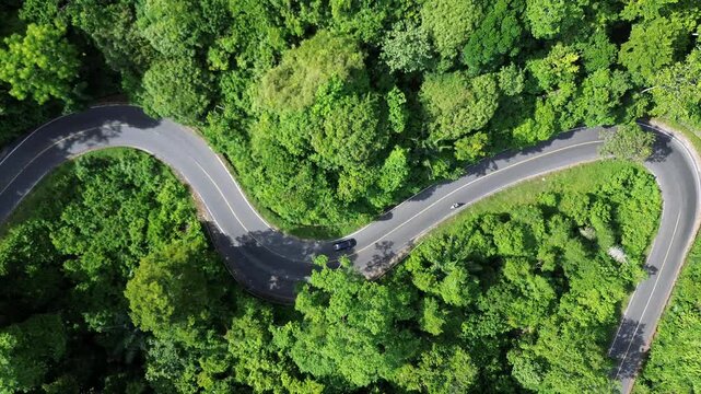 Aerial view of a minivan driving along a winding mountain road.