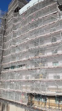 Basingstoke Hampshire England UK. 02.08.2026. Video.  A large building is completely covered in white netting and scaffolding, indicating ongoing construction or repair work on its facade