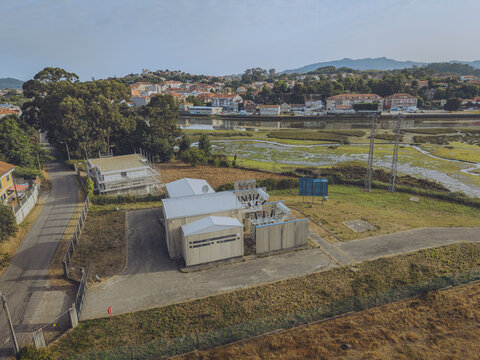 Aerial view of Subestacao E-Redes Gondomar, an electrical substation with white buildings and equipment, located near a riverbank in Sao Cosme, Porto District, Portugal.