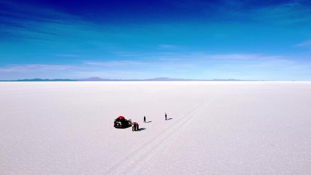 Aerial view of an off road vehicle and travelers exploring the vast, surreal landscape of the salar de uyuni salt flat in bolivia. Uyuni salt flats, bolivia
