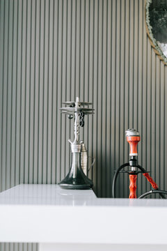 Modern shisha pipes standing on a white counter against a textured grey wall inside a lounge area