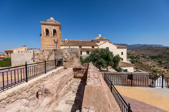 The Church of Santa Mar&iacute;a la Real in Aledo, Region of Murcia, Spain, with the remains of the medieval city wall in the foreground