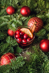 Fototapeta premium Mulled wine with orange, cranberry and cinnamon in fir forest setting. Selective focus.