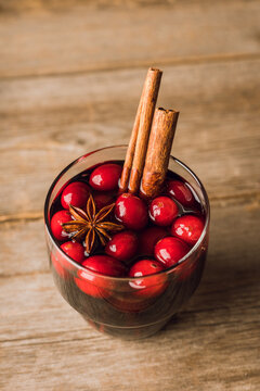 Mulled wine with orange, cranberry and cinnamon on rustic wooden background. Selective focus.