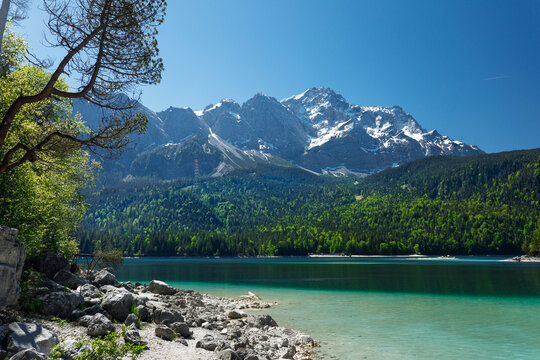 Travel landscape of Zugspitze Alps in Bavaria, Germany, scenic summer nature panorama with forest, Eibsee lake, snow mountains peak. Alpine landscape