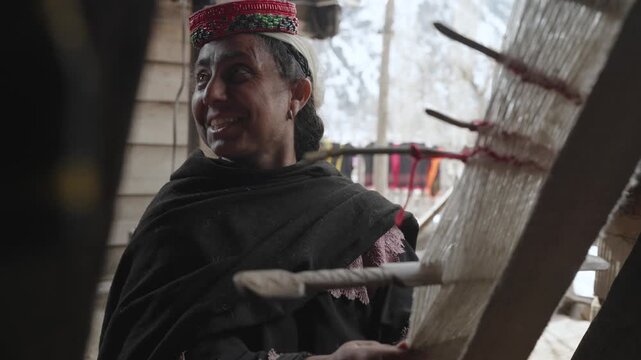 Indigenous Kalash Woman weaves a traditional Pakistan Carpet of Multicolored wool. Weaving and making handmade carpets.