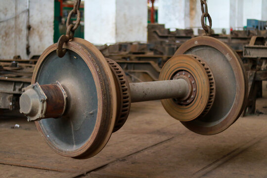 Heavy Industrial Train Axle with Brake Discs Suspended by Steel Chains in Workshop