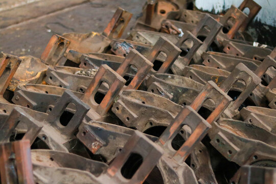 Pile of Heavy Cast Iron Mechanical Axle Boxes and Brackets in Industrial Workshop