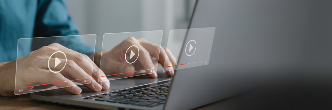 Close-up of a person typing on a laptop with digital video player interfaces floating in the air