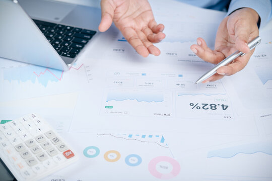 Businessman explaining performance marketing data with charts, analytics report, and calculator at office desk, concept of digital marketing strategy, business growth, and financial reporting.