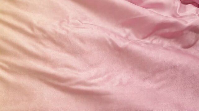 Close view of pink satin fabric shifting through three frames, highlighting flowing folds, glossy texture, elegant drapery, and abstract textile movement