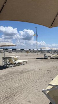 Beach with rows of umbrellas and chairs on traditional beach Tuscany Italy.	