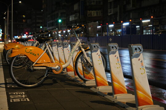 Shared public bicycles parked at a rental station at night.