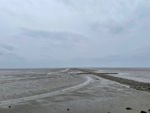 An der Nordseek&uuml;ste in B&uuml;sum ist an diesem Vormittag Ebbe. Das Wasser ist abgelaufen, und es ist ein sich windender Priel im Watt sichtbar. Daneben ist eine Buhne zum K&uuml;stenschutz.