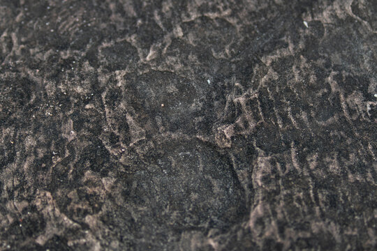 Dark weathered ancient stone surface background texture with organic erosion.
