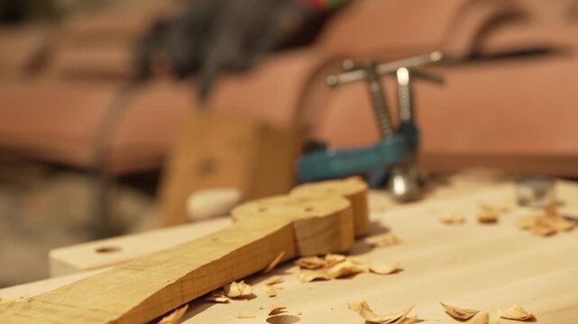 The master crafts traditional wooden string instruments by hand. The traditional musical instrument is the Calabrian lyre. The master works in the cozy light of his workbench.