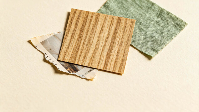 Wood grain sample rests atop textured cloth and torn paper. Soft lighting highlights natural tones and subtle textures. Composition evokes warmth, simplicity, and earthy aesthetics