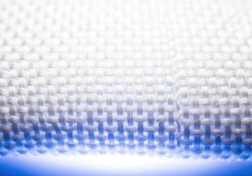 Detailed close-up of a sterile medical textile sample positioned under a professional laboratory microscope with bright scientific lighting, healthcare, testing, precision