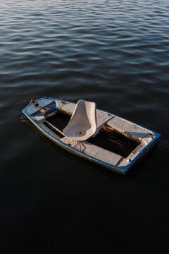 Old boat floating on calm water with a white seat inside