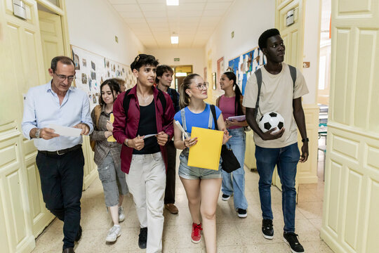 Diverse students and teacher walking school hallway