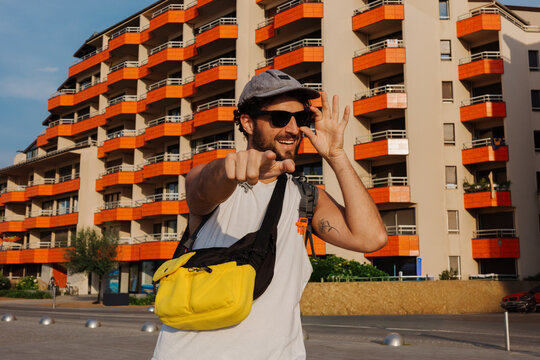 A man stands outside in front of buildings with orange balconies