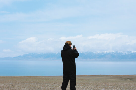 A Traveler Photographing the Scenery by the Shore of Sayram Lake.