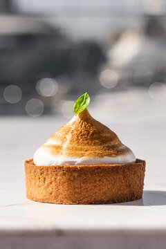 Gourmet lemon meringue tartlet on a white marble surface