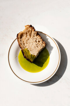 Pouring vibrant green olive oil onto a slice of sourdough bread