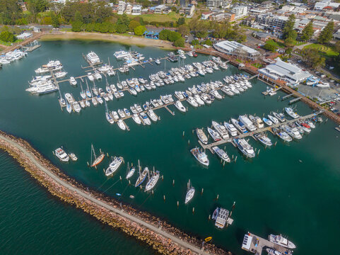 Rows of boats behind a rock breakwater alongside a coastal town