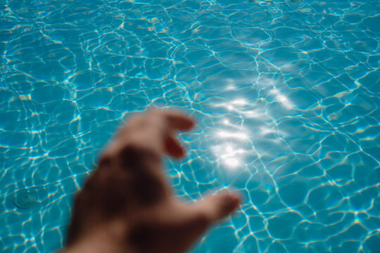 Reaching Toward Sunlight Reflected On Swimming Pool Water