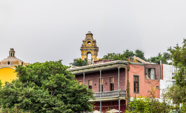 A view of colourful historic colonial style buildings and a yellow church bell tower in the bohemian Barranco district of Lima, Peru