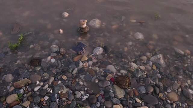 Defocused Sacred River Bathing at Devghat Dham, Nepal, with Balanced River Stones in Foreground, Hindu Pilgrimage, Spiritual Ritual, Peaceful Riverside Landscape and Cultural Heritage