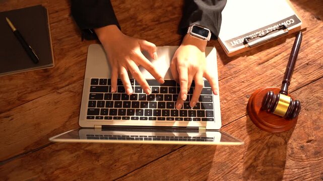 Legal Expertise Online: Hands typing on a laptop with a gavel and law book nearby, symbolizing legal services accessed digitally.