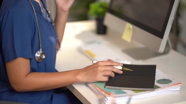 Medical Professional at Desk: A doctor or nurse in blue scrubs, with a stethoscope around their neck, works at a desk with a computer and notebook, illuminated by the soft glow of desk lamp.
