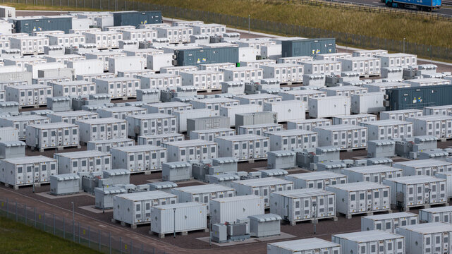 Aerial view of BESS Wind turbine battery units, featuring rows of white energy storage containers arranged in a grid pattern on a gravel site in Lanark, Scotland, United Kingdom.