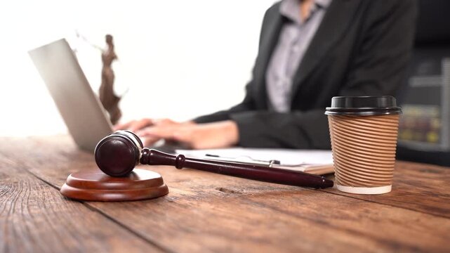 Justice and Law at Work: A close-up shot captures a gavel and a laptop on a wooden desk, symbolizing the legal profession, with a coffee cup nearby.