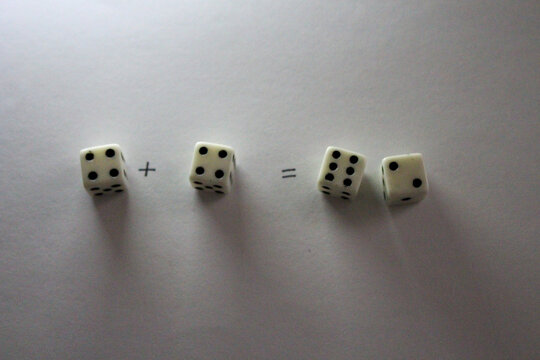 An addition math problem shows white dice&mdash;displaying numbers An addition math problem shows white dice&mdash;displaying numbvia their dots&mdash;on a white background, casting shadows. four plus four equals eight