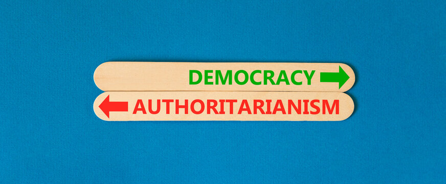 Democracy or authoritarianism words symbol. Concept words Democracy Authoritarianism on beautiful wooden sticks. Beautiful blue background. Business democracy authoritarianism concept. Copy space