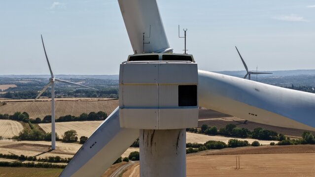 Aerial view of the Penny Hill Wind Farm featuring a large wind turbine nacelle and blades set against a rural landscape of agricultural fields in Aston, England, United Kingdom.