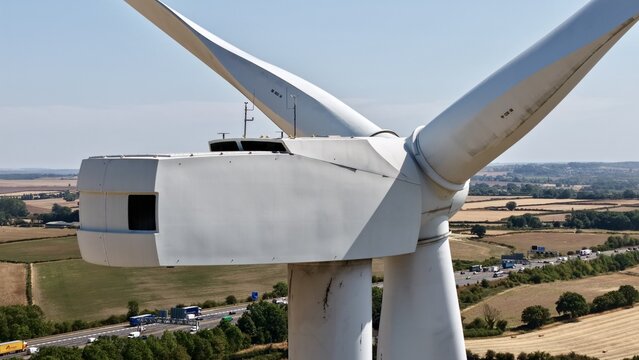 Aerial view of Penny Hill Wind Farm nacelle and blades with a highway and rural fields in the background in Aston, England, United Kingdom.