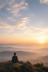 Naklejka premium Man meditating on a mountain summit overlooking misty hills at sunrise. Peaceful mindfulness, spiritual reflection, nature escape, wellness and mental health concept with copy space.