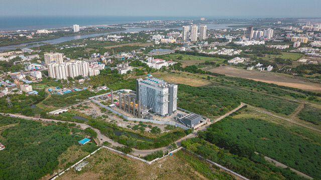 Aerial view of a modern data center facility surrounded by lush greenery and urban development in Chennai, Tamil Nadu, India.