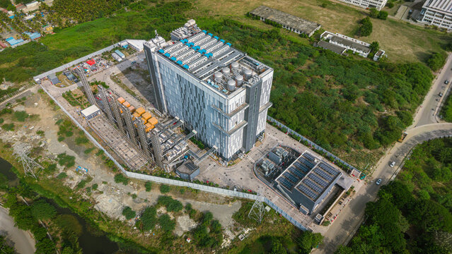 Aerial view of a large modern data center facility featuring rooftop cooling units, solar panels, and industrial infrastructure surrounded by lush greenery in Chennai, Tamil Nadu, India.