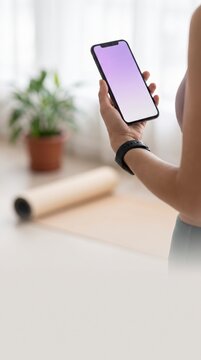 Serene hand holding purple gradient smartphone mockup screen near yoga mat at home