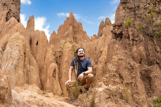 Smiling Man Crouching in Eroded Clay Rock Valley. Tatacoita - Nemocon